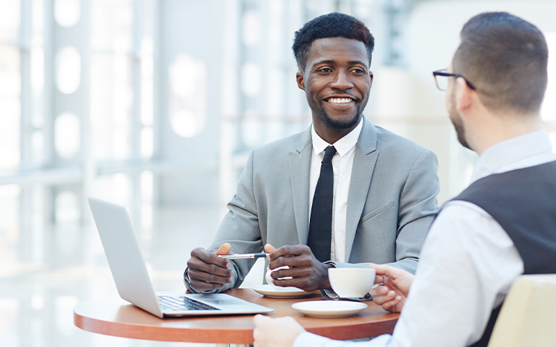 Two people sitting at table in front of a laptop